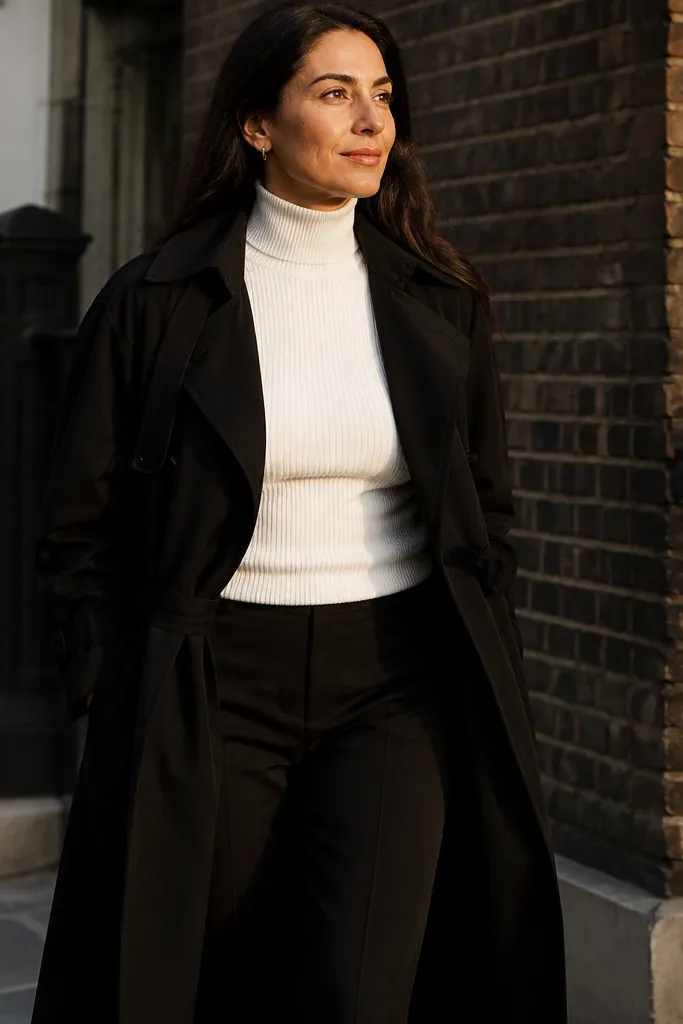 Black trench over white turtleneck with straight-leg black trousers and black pointed flats