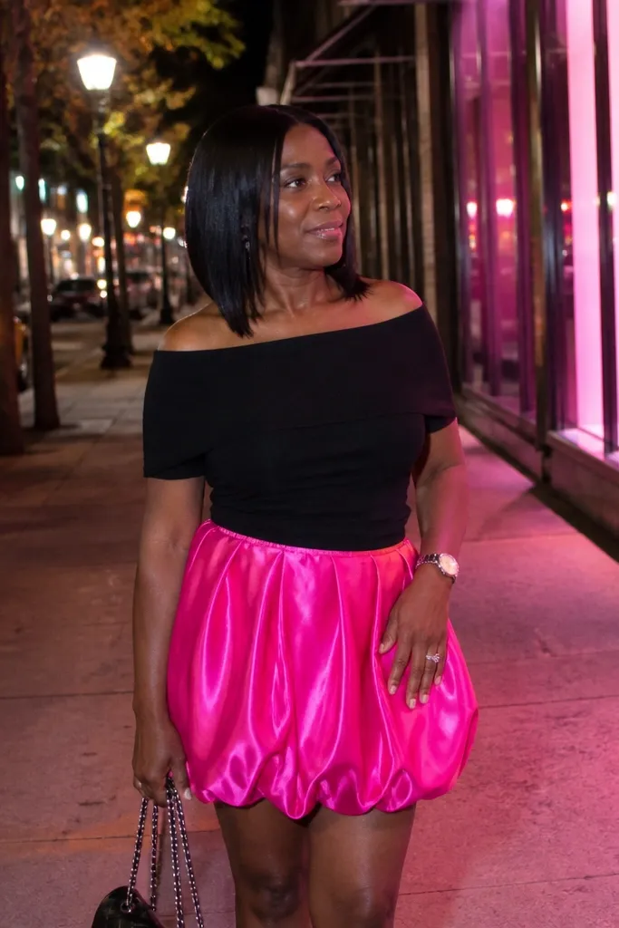 Hot pink bubble mini skirt with a black off-shoulder top and black strappy heels