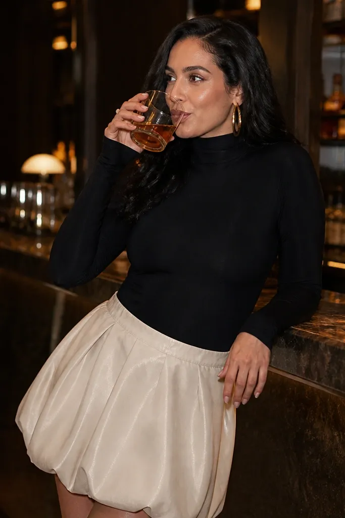 Cream bubble mini skirt with a black bodysuit and gold hoop earrings