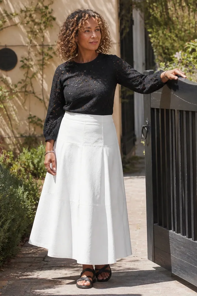 Black eyelet blouse with a white A-line skirt and black strappy sandals