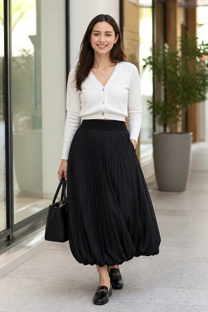 Black micro-pleat long bubble skirt with a white cropped cardigan and loafers